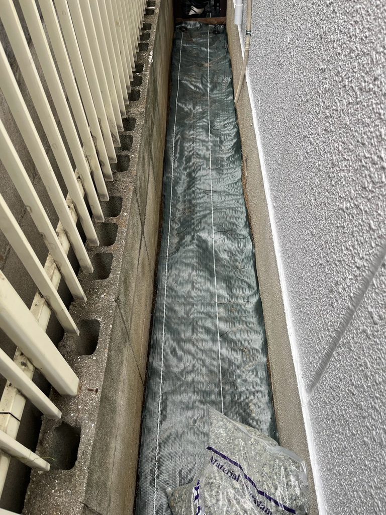 尼崎市の家まわりに防草シートを施工している様子